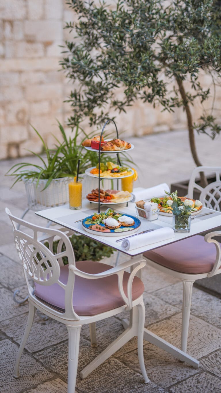 Three-tier breakfast stand with pastries, fresh fruit, cheeses and cured meats.