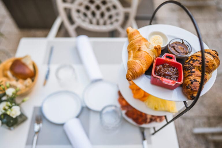 Three-tier breakfast stand with pastries, fresh fruit, cheeses and cured meats.