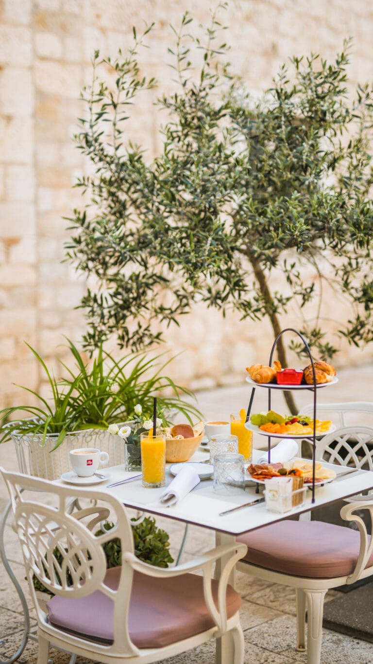Three-tier breakfast stand with pastries, fresh fruit, cheeses and cured meats.