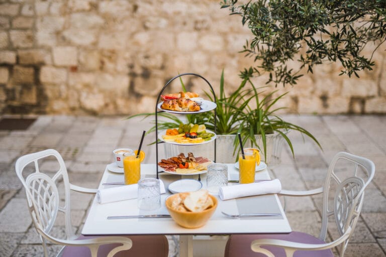 Three-tier breakfast stand with pastries, fresh fruit, cheeses and cured meats.